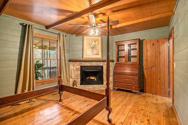 sitting room featuring a fireplace, wooden walls, light hardwood / wood-style flooring, and beamed ceiling