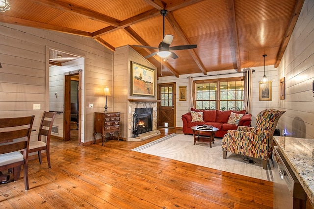 living room with wood walls, lofted ceiling with beams, light hardwood / wood-style flooring, ceiling fan, and wood ceiling