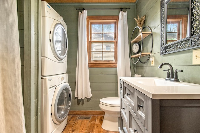 washroom featuring sink, stacked washing maching and dryer, and light hardwood / wood-style flooring