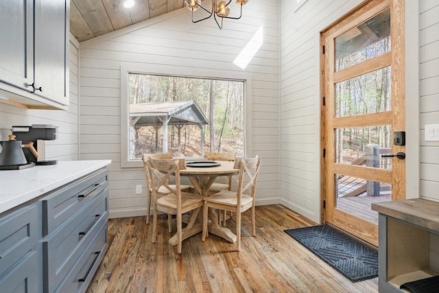 dining area featuring a wealth of natural light, wooden walls, and light hardwood / wood-style flooring