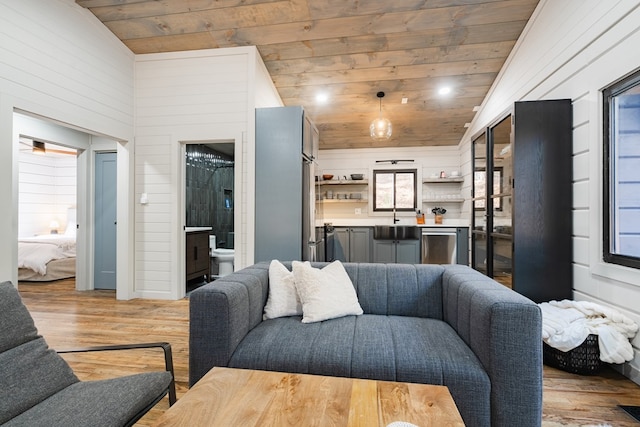 living room featuring wood walls, light hardwood / wood-style floors, sink, high vaulted ceiling, and wood ceiling