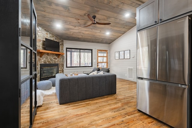 living room featuring wooden ceiling, ceiling fan, a fireplace, lofted ceiling, and light wood-type flooring