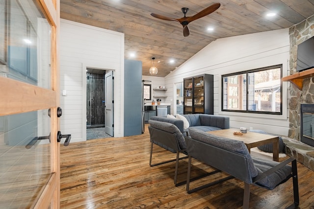 living room featuring a fireplace, hardwood / wood-style flooring, wooden walls, and vaulted ceiling