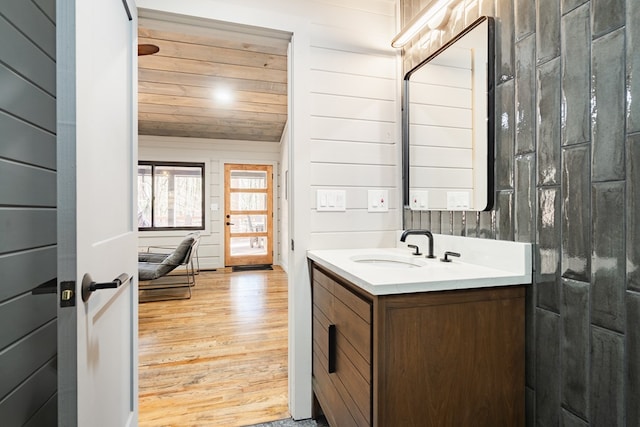 bathroom featuring hardwood / wood-style floors, wood walls, wood ceiling, and vanity