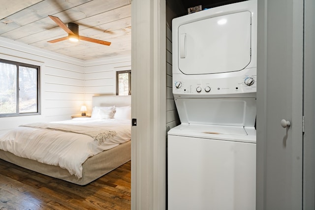 bedroom with ceiling fan, wood ceiling, stacked washer / dryer, wooden walls, and dark hardwood / wood-style flooring