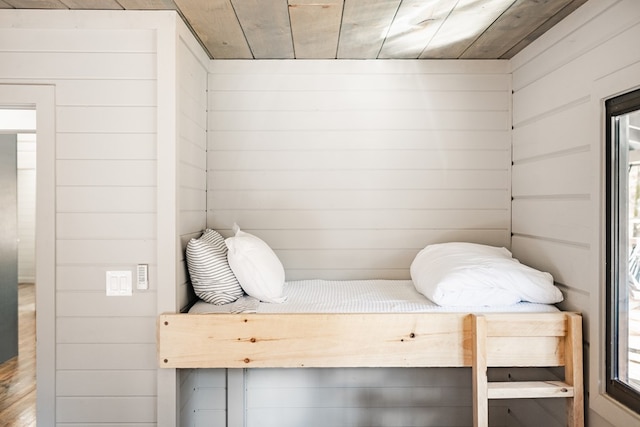 bedroom with hardwood / wood-style floors, wooden walls, and wooden ceiling