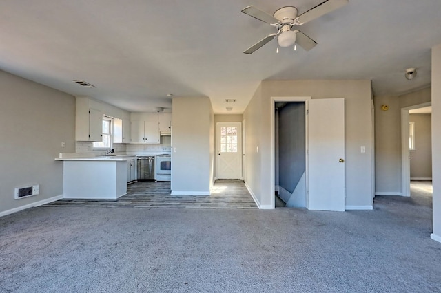 unfurnished living room with carpet flooring, ceiling fan, and sink