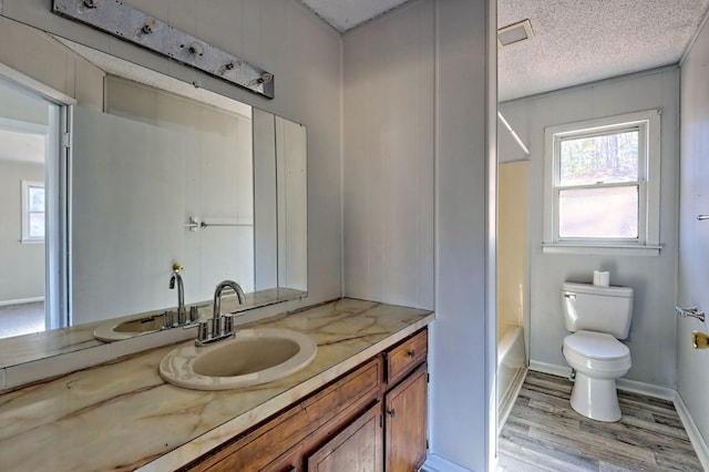 full bathroom featuring vanity, a textured ceiling, hardwood / wood-style flooring, and toilet