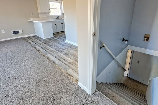 stairway with sink and hardwood / wood-style flooring