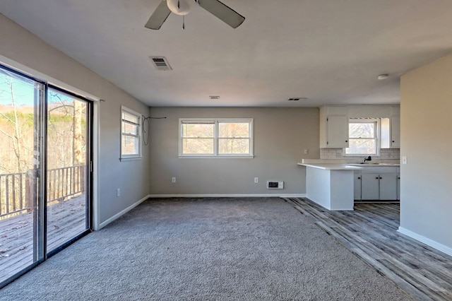 unfurnished living room with carpet, a wealth of natural light, and ceiling fan