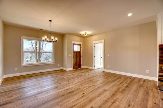 interior space with a wealth of natural light, light hardwood / wood-style flooring, and a notable chandelier