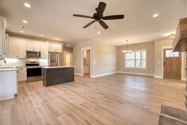 kitchen featuring white cabinets, appliances with stainless steel finishes, a center island, and light wood-type flooring