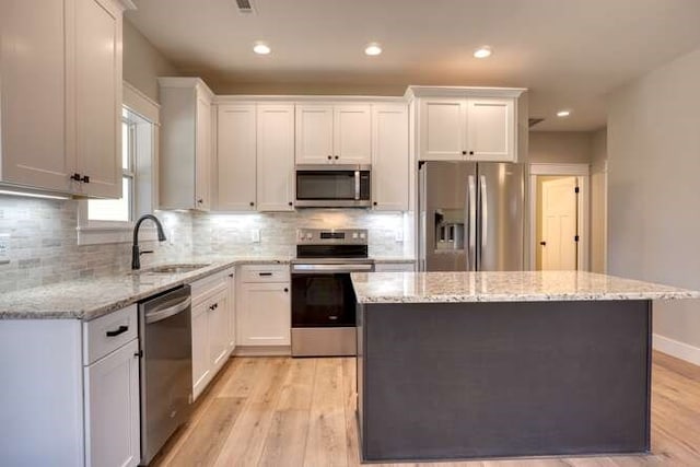 kitchen with light hardwood / wood-style floors, white cabinetry, sink, and appliances with stainless steel finishes