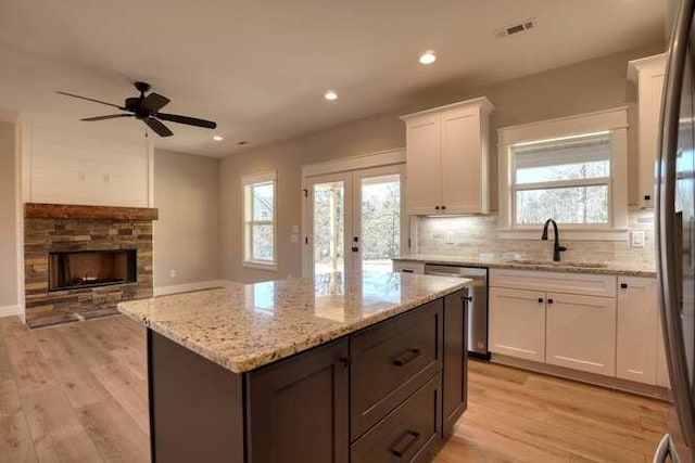 kitchen featuring stainless steel appliances, white cabinetry, a kitchen island, and light hardwood / wood-style flooring