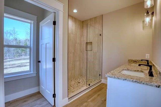 bathroom with hardwood / wood-style floors, vanity, and a shower with shower door