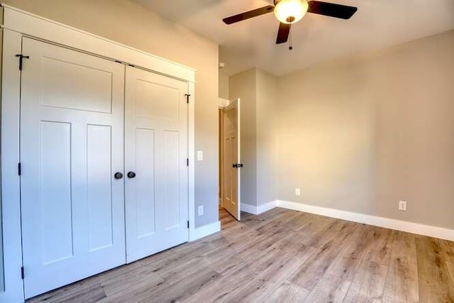 unfurnished bedroom featuring ceiling fan, a closet, and light wood-type flooring