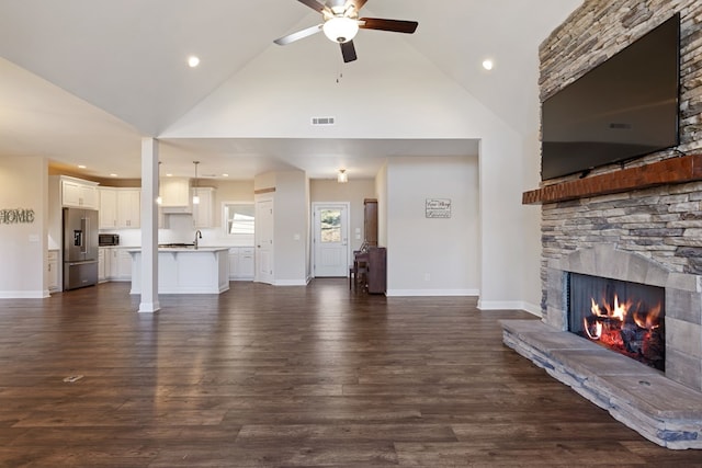 unfurnished living room with a ceiling fan, dark wood-style floors, visible vents, a fireplace, and a sink