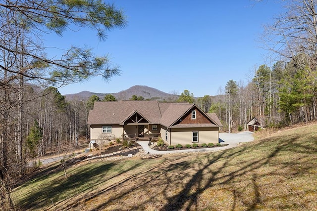 craftsman-style house featuring a mountain view, a porch, a view of trees, and a front lawn