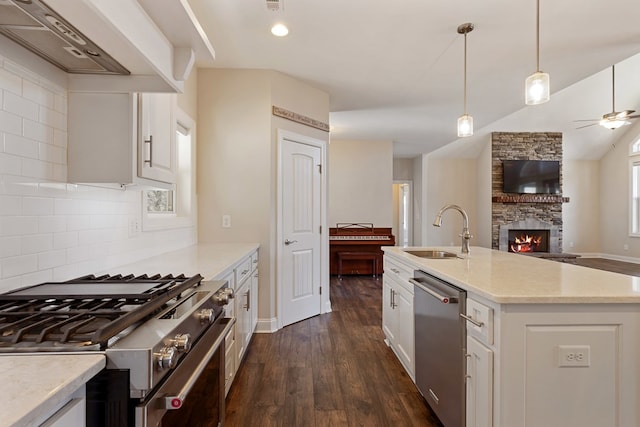 kitchen featuring a sink, open floor plan, dark wood finished floors, appliances with stainless steel finishes, and wall chimney range hood