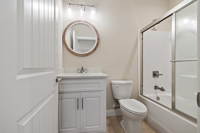 bathroom featuring combined bath / shower with glass door, baseboards, toilet, and vanity