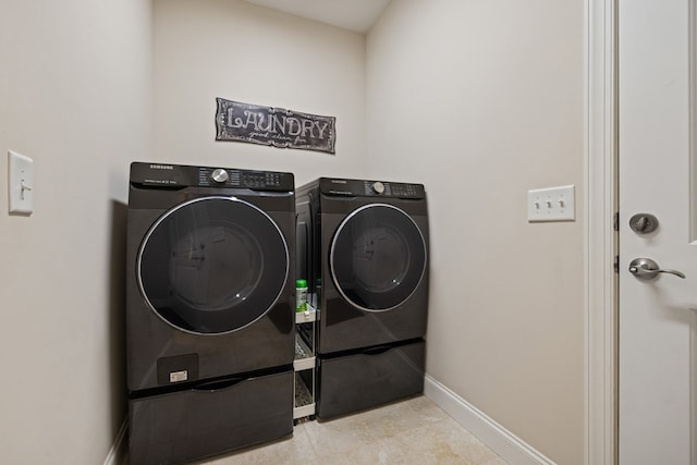 washroom with laundry area, washing machine and dryer, and baseboards