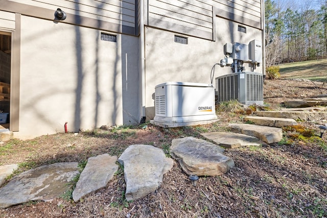 exterior space with central AC unit, a power unit, and stucco siding