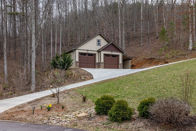 view of front of home with a wooded view, a front yard, a garage, an outdoor structure, and stone siding