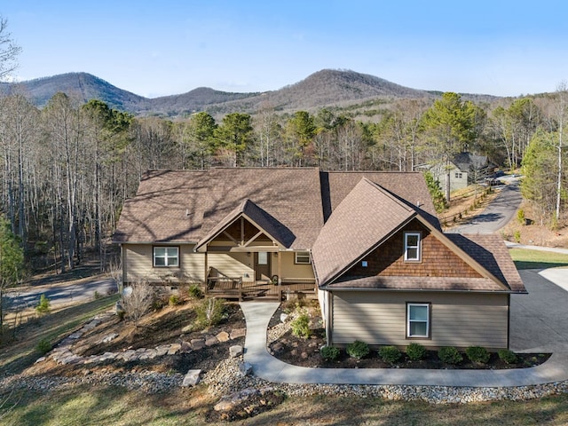 view of front facade featuring a chimney, a mountain view, a view of trees, and roof with shingles