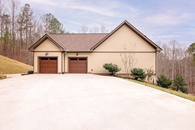 view of side of home with an attached garage and a shingled roof