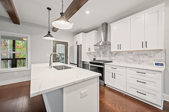 kitchen featuring wall chimney range hood, sink, an island with sink, stainless steel appliances, and white cabinets