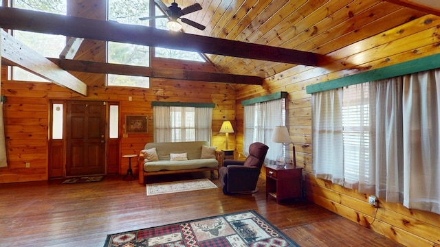 living room with a ceiling fan, hardwood / wood-style flooring, wood walls, and vaulted ceiling with skylight