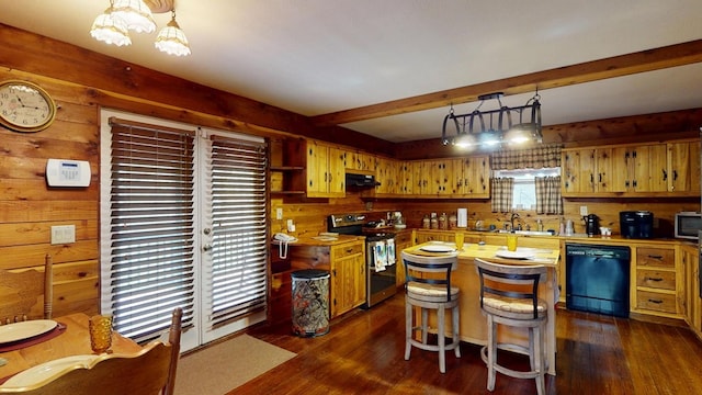 kitchen with under cabinet range hood, wood walls, appliances with stainless steel finishes, and a sink