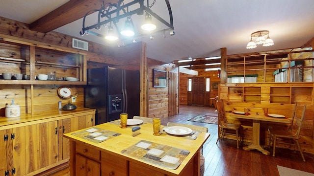 kitchen featuring wooden walls, black fridge with ice dispenser, butcher block countertops, and visible vents