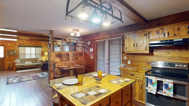 kitchen featuring wooden walls, under cabinet range hood, dark wood-type flooring, and range with two ovens