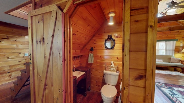 bathroom featuring toilet, wooden walls, wooden ceiling, hardwood / wood-style flooring, and vaulted ceiling