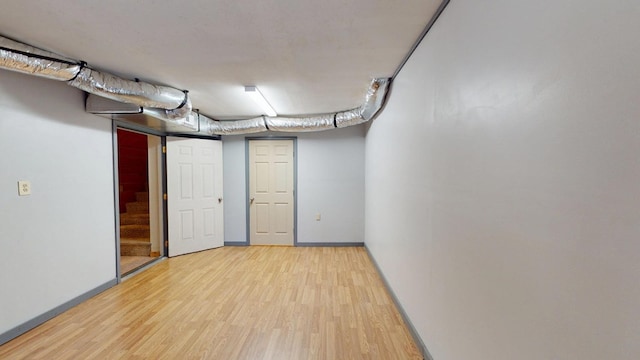 finished below grade area featuring baseboards, wood finished floors, and stairway