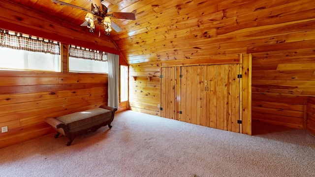 living area with carpet floors, lofted ceiling, wooden walls, wood ceiling, and a ceiling fan