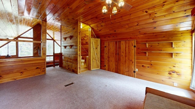bonus room with carpet floors, wood walls, a ceiling fan, lofted ceiling, and visible vents