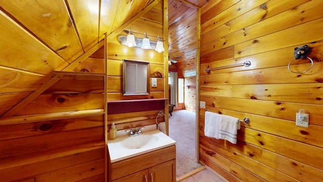 bathroom featuring vanity, tile patterned floors, vaulted ceiling, and wood walls