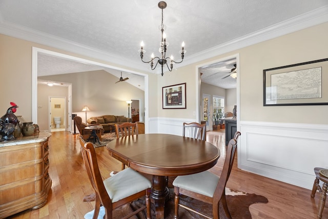 dining room featuring a textured ceiling, light wood-type flooring, crown molding, and ceiling fan with notable chandelier