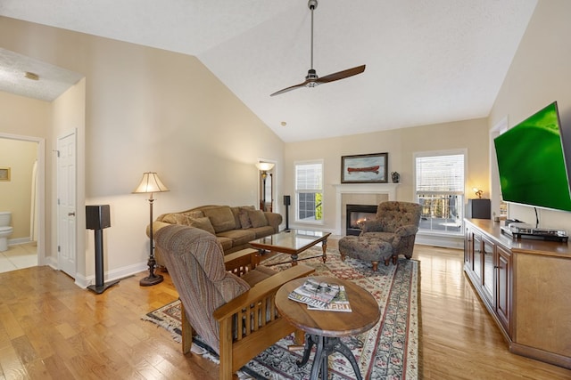 living room with a healthy amount of sunlight, ceiling fan, light hardwood / wood-style flooring, and high vaulted ceiling