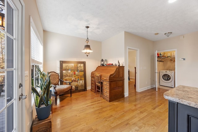 sitting room with washer / clothes dryer, light hardwood / wood-style floors, and a textured ceiling