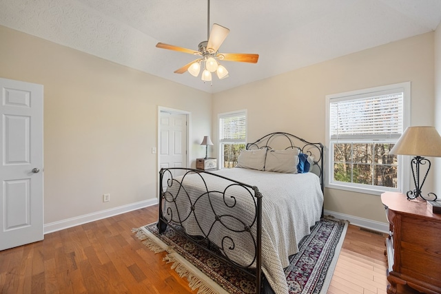 bedroom featuring hardwood / wood-style floors, ceiling fan, and multiple windows