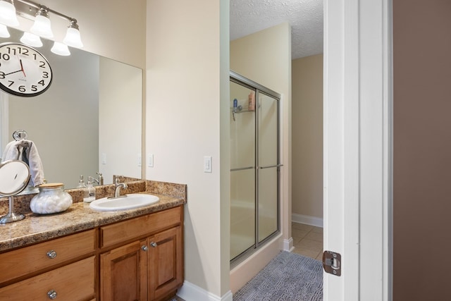 bathroom featuring a textured ceiling, a shower with door, tile patterned floors, and vanity