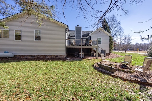 back of house with an outdoor fire pit, a lawn, and a wooden deck