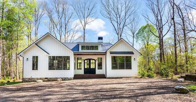 modern inspired farmhouse featuring french doors, a chimney, and metal roof