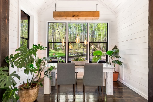 dining area featuring wood walls, dark wood-style floors, and lofted ceiling