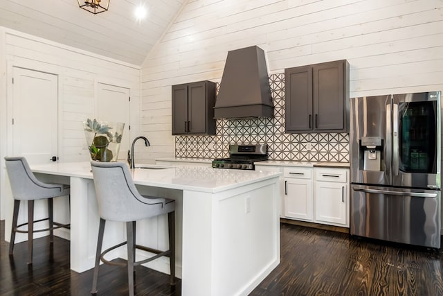 kitchen with appliances with stainless steel finishes, dark wood finished floors, a sink, premium range hood, and lofted ceiling