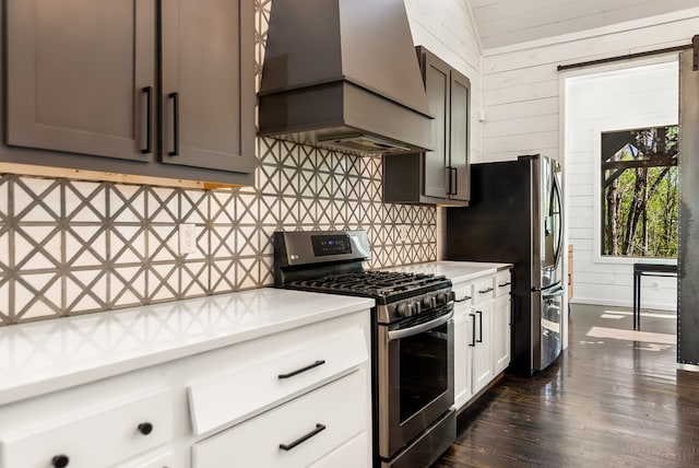 kitchen featuring wooden walls, appliances with stainless steel finishes, light countertops, custom range hood, and tasteful backsplash