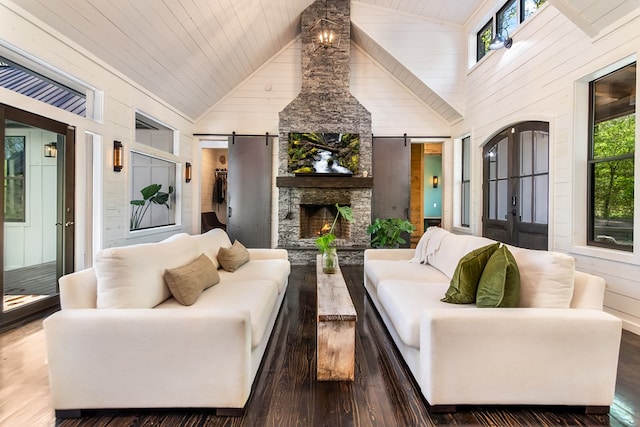 living area featuring a barn door, wood finished floors, a wealth of natural light, and wood walls